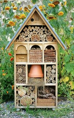 a bird house with lots of bees in it's roof and flowers around it