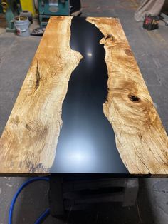 a table made out of wood and black epe in the center, with a blue hose connected to it