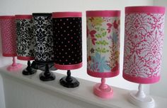 five vases are lined up on a shelf with pink and black trim around them