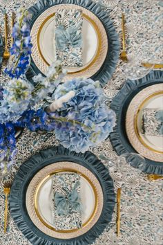 the table is set with blue and white plates, silverware, and floral centerpieces