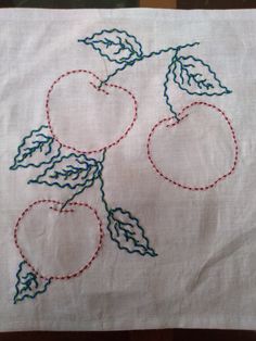 an embroidered piece of cloth with two cherries on it