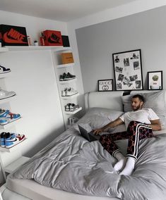 a man laying on top of a bed in a bedroom next to a book shelf