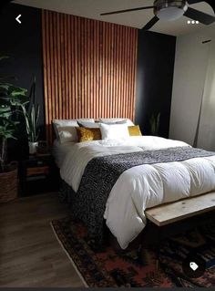 a bed with white sheets and pillows in a bedroom next to a wooden headboard