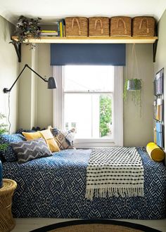 a bedroom with a bed, bookshelf and baskets on the shelves above it