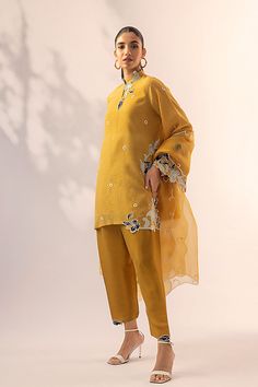 An ethereal mustard khaddi corduroy shirt elevated with applique accents adorning its neckline, sleeves and hemline. This outfit is paired with a co-ord rawsilk shalwar and an organza dupatta embellished with white pom-poms and scalloped cutwork borders. This classy yet stylish ensemble will enhance your look this fest Yellow Silk Sharara With Dabka, Yellow Silk Sharara With Dabka Details, Spring Unstitched Cotton Silk Traditional Wear, Yellow Long-sleeved Kurta With Sheer Dupatta, Yellow Long-sleeved Raw Silk Salwar Kameez, Yellow Long Sleeve Kurta With Sheer Dupatta, Yellow Long Sleeve Raw Silk Kurta, Yellow Raw Silk Kurta With Dabka, Yellow Cotton Silk Kurta With Sheer Dupatta