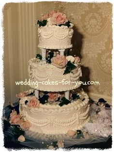 a three tiered wedding cake with pink flowers on the top and bottom, sitting on a table in front of a wall