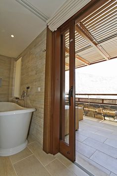 a bath tub sitting next to a wooden door in a bathroom under an awning