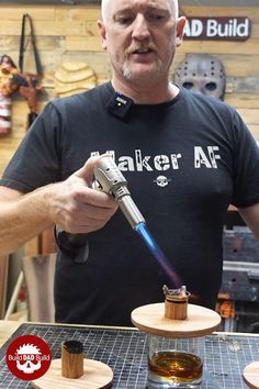 a man holding a lighter in his right hand while standing next to other items on a table