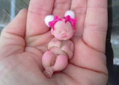 a hand holding a tiny baby doll in it's palm