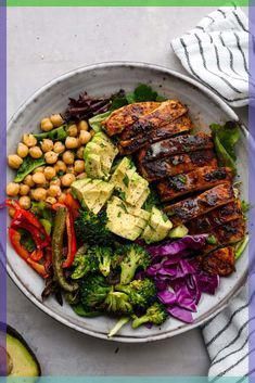 a plate filled with meat, vegetables and chickpeas on top of a table