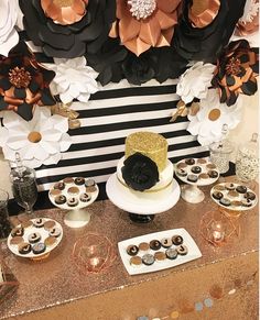 there is a cake and cupcakes on the table with black and gold decorations