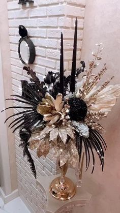 a vase filled with black and white flowers on top of a table next to a brick wall