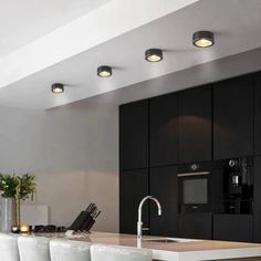 a modern kitchen with black cabinets and white stools