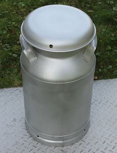 a large metal container sitting on top of a white tablecloth covered floor next to green grass