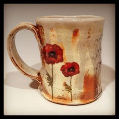 a ceramic mug with red flowers painted on it