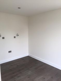 an empty room with wood floors and white walls