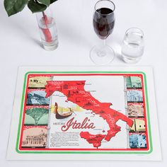 there is a place mat with the map of italy on it and two wine glasses next to it