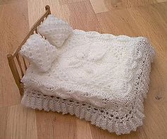 a white crocheted blanket and pillow on a wooden bed frame with wood flooring