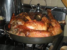 a large cooked turkey sitting in a pan on the stove