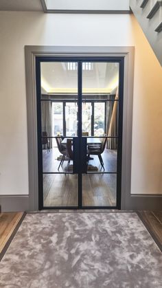 an open door leading to a living room and dining area with stairs in the background