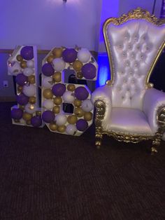 a chair and balloon letters sitting in front of a purple wall with lights on it