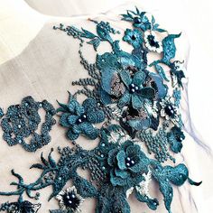 the back of a dress with blue flowers and beads on it's neckline