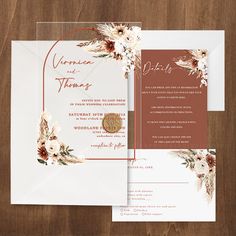 an elegant wedding card with flowers on the front and back, is displayed against a wooden background