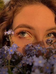 a close up of a woman's face with flowers in front of her eyes