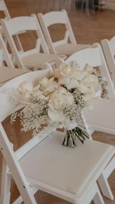 a bouquet of flowers sitting on top of a white chair in front of rows of chairs