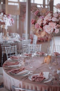 the table is set with pink flowers and place settings