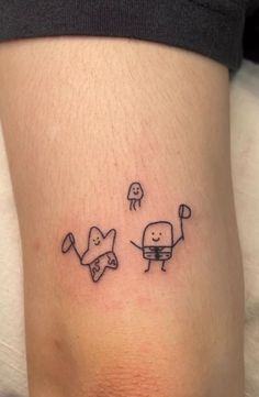 a small tattoo on the leg of a woman with two little monsters flying above her