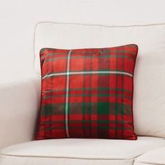 a red and green plaid pillow sitting on top of a white couch