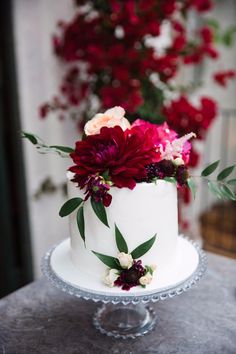 a white cake with red and pink flowers on top