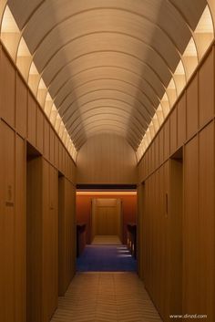 an empty hallway with wooden walls and blue carpeting on the floor is lit by recessed lighting