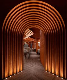 an arched hallway with wooden flooring and lighting on the walls is lit up at night