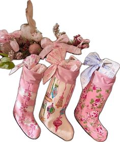 three pink christmas stockings with bows and flowers in the bottom one is tied to a tree