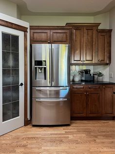 a metallic refrigerator freezer sitting inside of a kitchen next to wooden cabinets and drawers