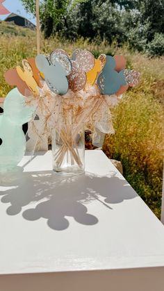 a vase filled with flowers sitting on top of a white table covered in paper leaves