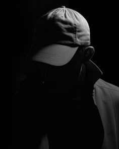 a black and white photo of a man wearing a baseball cap with his head turned to the side