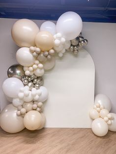 white balloons are floating in the air near a sculpture with silver and white balls on it