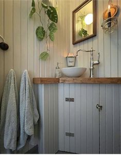 a bathroom sink sitting under a mirror next to a towel rack and potted plant