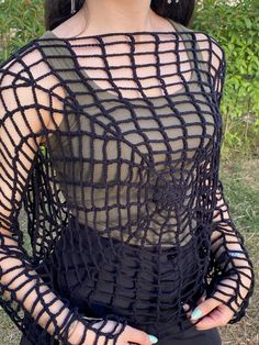 a woman with long black hair is posing for the camera in front of some bushes