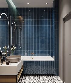 a blue tiled bathroom with a tub, sink and mirror