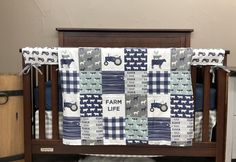 a baby crib with a farm life quilt on it