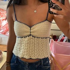 a woman taking a selfie with her cell phone and wearing a crocheted top