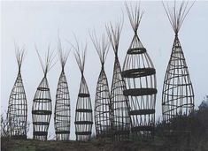 several metal sculptures are lined up on the side of a hill with trees growing out of them