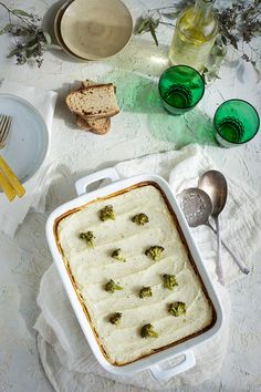 a casserole dish with broccoli in it on a white tablecloth