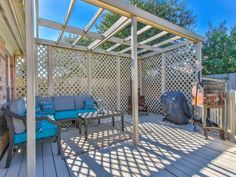 an outdoor living area with wooden decking and pergolated walls, covered in blue cushions