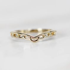 a gold wedding band with small diamonds on the sides and an oval design in the middle