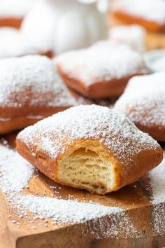 powdered sugar covered pastries sit on a cutting board